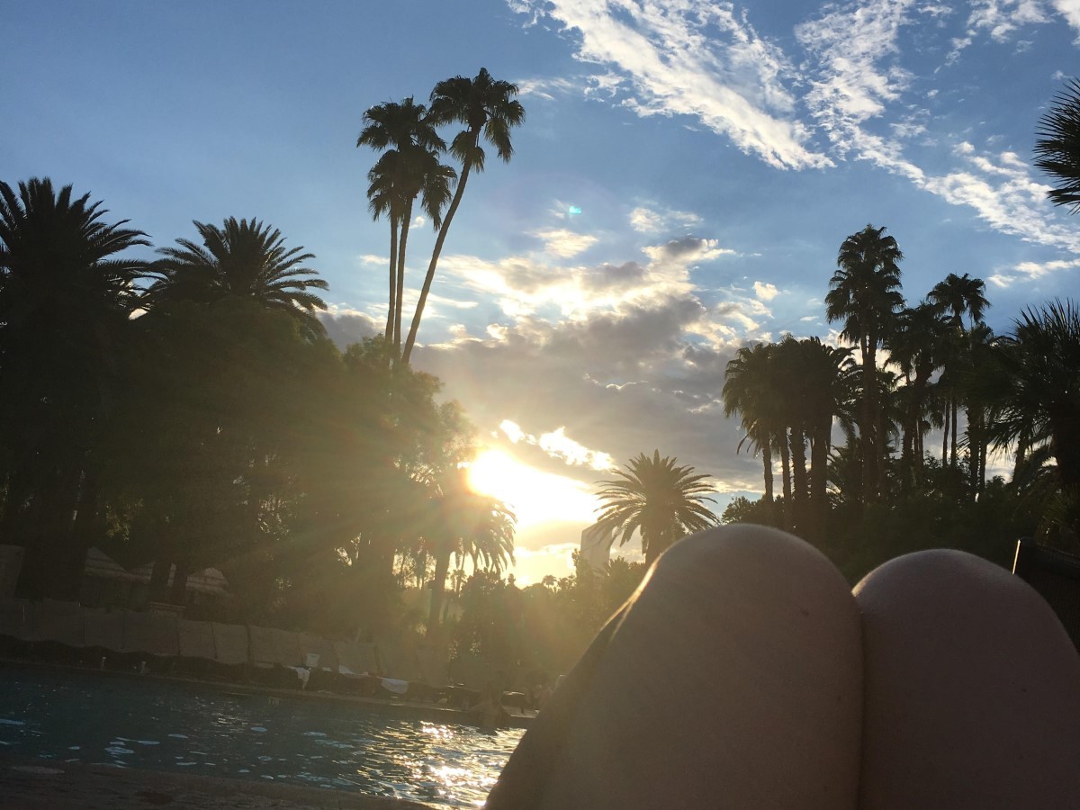 Neurodermitis-Kunstaktion #perspektivwechsel! – Foto von angewinkelten Beinen, im Hintergrund Wasser, Palmen, Sonne und blauer Himmel.